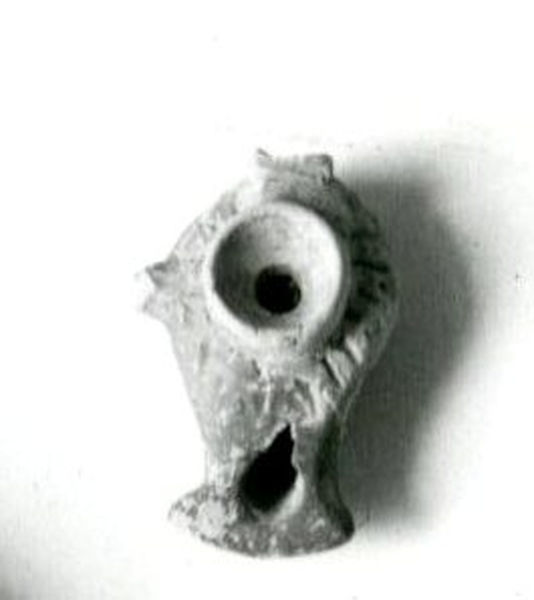 002702 - reperto - Casa Repubblicana a fianco delle Scalae Caci (sud-ovest della Casa di Livia), deposito di vasellame sopra la volta del "camerone" sostruttivo (angolo S/E), durante gli scavi del Carettoni del 1956.  Piccola lucerna a vernice rossa, monolicne, con becco a testa d'incudine, piccola appendice laterale ed anello sopraelevato attorno al foro centrale. Priva di ansa. Sul fondo sono impressi cinque cerchietti. 

Bibliografia: Carettoni, G.F. in NsC 1967 pag.303

Neg. serie F nÂ°2401