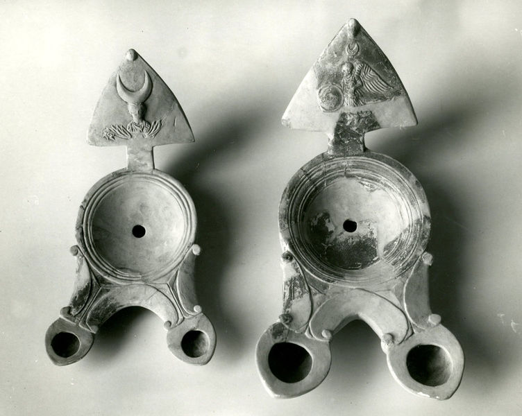 002705 - reperto - Casa Repubblicana a fianco delle Scalae Caci (sud-ovest della Casa di Livia), ambiente I, colmatura (scarico superficiale di terra arenosa), durante gli scavi del Carettoni del 1956.  Coppia di Lucerne a due luci (bilicne)  a volute con ansa triangolare decorata.

Bibliografia: Carettoni, G.F. in NsC 1967 pag.306

Neg. serie F nÂ°2399